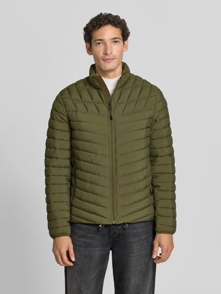 Männermodel trägt Steppjacke mit Label-Patch Modell 'LAPAZ' von Napapijri in Olivgrün, Reißverschluss, Seitentaschen, Ganzkörperansicht von vorne.