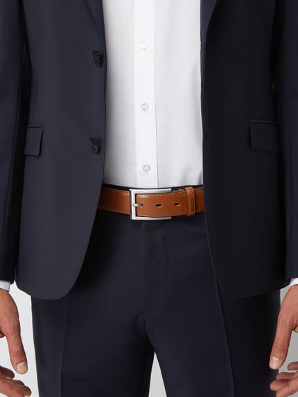 Männermodel trägt Ledergürtel mit Dornschließe und Label-Detail von Lloyd Men's Belts, klassisch braun, Nahaufnahme Oberkörper.