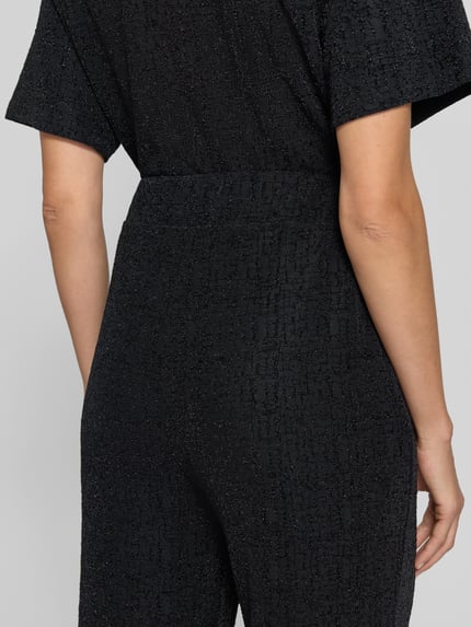 Frauenmodel trägt 'Schimmere Hose mit elastischem Bund Modell 'NAREEN' von ICHI aus Material-Mix, schwarze Struktur, Nahaufnahme Rückansicht, Regular Fit, Stretch-Anteil.