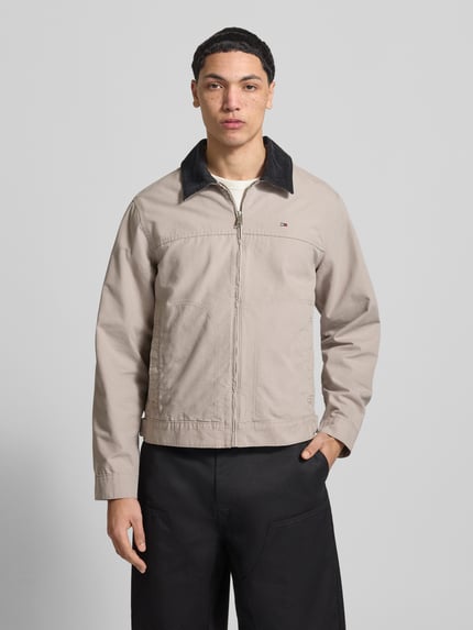 Männermodel trägt Regular Fit Ranch-Jacke aus reiner Baumwolle von Tommy Jeans in beige mit Umlegekragen aus Cord, Ganzkörperansicht von vorne.
