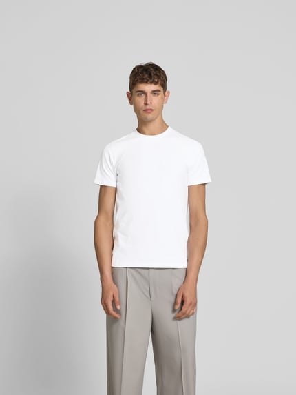 Männermodel trägt Slim Fit T-Shirt aus Baumwoll-Elasthan-Mix von Filippa K, weiß, mit Rundhalsausschnitt, Herren T-Shirt, Ganzkörperansicht von vorne.