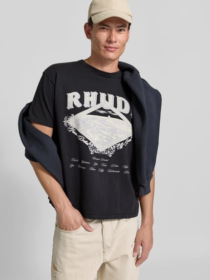 Männermodel trägt Regular Fit T-Shirt aus reiner Baumwolle von RHUDE in Schwarz mit Label-Print und Rundhalsausschnitt, Nahaufnahme Oberkörper.