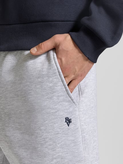 Männermodel trägt Slim Fit Sweatpants mit Logo-Stitching von REVIEW aus Baumwoll-Mix in Hellgrau, Nahaufnahme Oberkörper.