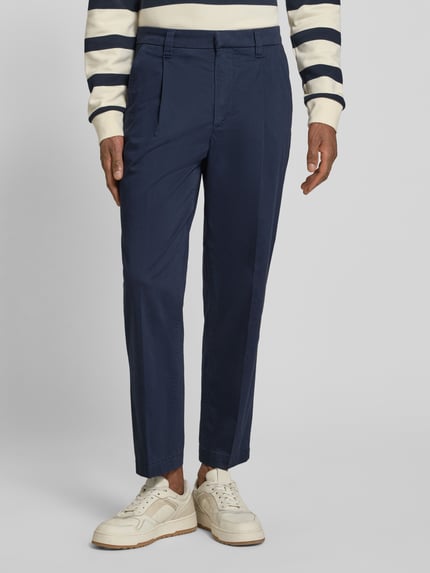 Männermodel trägt Regular Fit Chino aus Baumwoll-Mix Modell 'TAAMIR PLEATED' von Armedangels, unifarben, Mid Waist, Nahaufnahme Unterkörper.