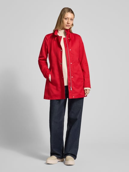 Frauenmodel trägt roten Trenchcoat mit Stehkragen und Eingrifftaschen von Fuchs Schmitt, Baumwoll-Mix, Ganzkörperansicht von vorne.