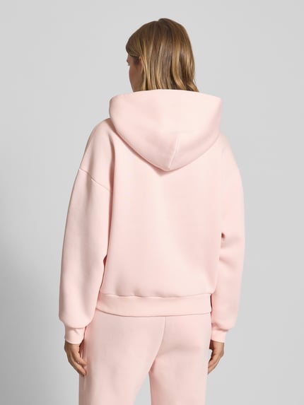 Frauenmodel trägt Hoodie mit Kapuze von Review in zartem Rosa, lockerer Schnitt, Baumwoll-Mix, Ganzkörperansicht Rückansicht.