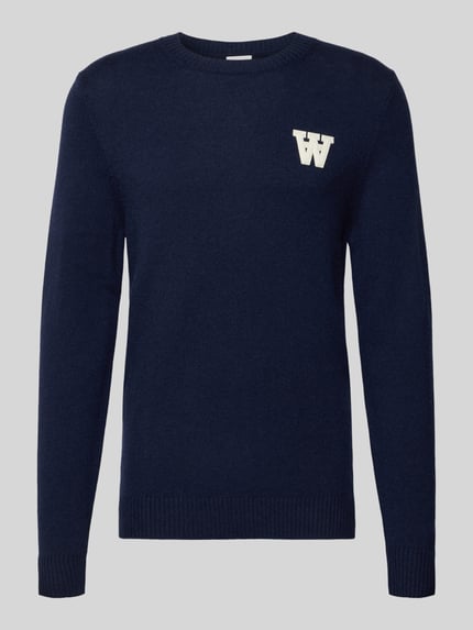 Produktfoto, dunkelblauer Strickpullover aus Lammwolle Modell 'Tay' von Wood Wood, Regular-Fit, cremefarbenes Label-Stitching, Rundhalsausschnitt