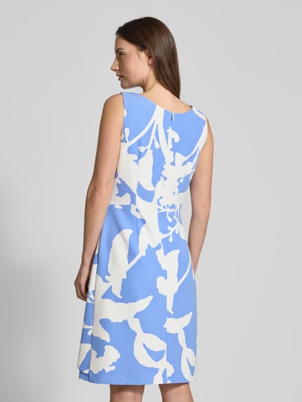 Vrouwenmodel draagt knielanges Cocktailkleid in Wickel-Optik van Vera Mont, blauw met witte print, taille fit, rugrits, rugaanzicht