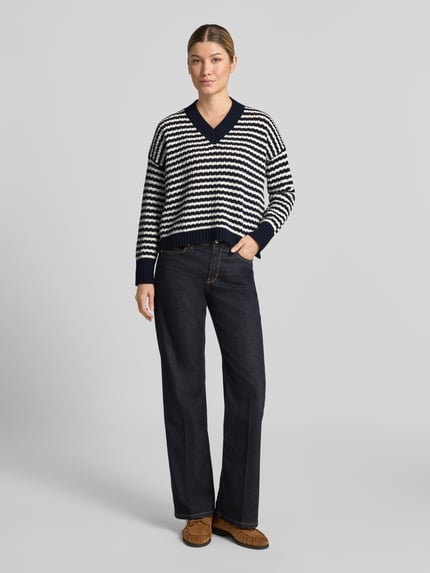 Kobiece model nosi sweter Loose Fit Pullover aus reiner Schurwolle Modell 'SPIGA' od Weekend Max Mara, ciemne kolory, pasy, widok całej sylwetki z przodu.