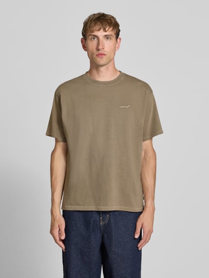 Männermodel trägt Relaxed Fit T-Shirt aus reiner Baumwolle Modell 'VINTAGE TEE' von Levi's®, beige, glatte Textur, Herren T-Shirt, Ganzkörperansicht von vorne.