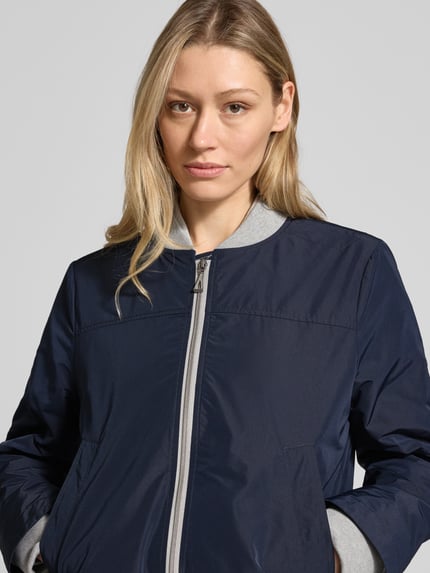 Vrouwenmodel draagt donkerblauwe bomberjack met opstaande kraag, tweewegritssluiting en steekzakken, regular fit, Bomberjacke mit Zweiwege-Reißverschluss van Amber & June, ruglengte maat 36: 59 cm, schouderbreedte: 37 cm, borstwijdte: 50 cm, mouwlengte: 66 cm, Nahaufnahme bovenlichaam.