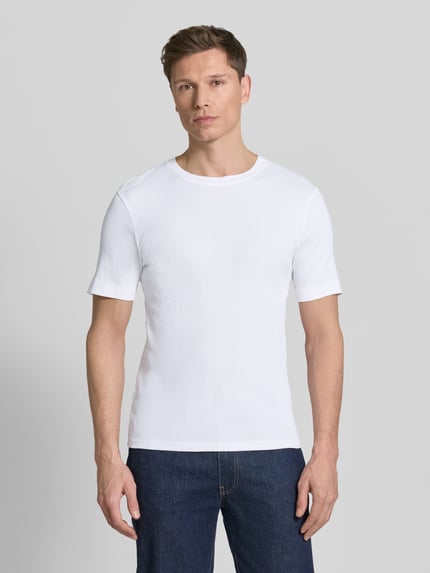 Männermodel trägt weißes Herren T-Shirt mit Rundhalsausschnitt Modell 'ENIL' von Drykorn aus reiner Baumwolle, Slim-Fit, Ganzkörperansicht von vorne. Rückenlänge bei Größe M: 66 cm.