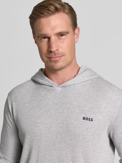 Männermodel trägt Regular Fit Hoodie aus Baumwoll-Mix von BOSS, hellgraue Farbe, feine Struktur, Nahaufnahme Oberkörper.