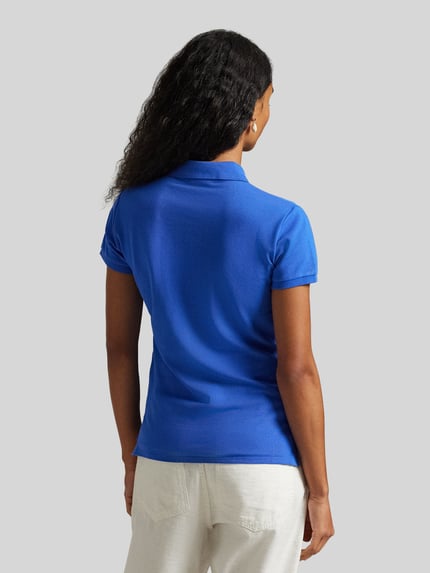 Frauenmodel trägt Slim Fit Poloshirt aus Baumwoll-Mix von Polo Ralph Lauren in Optik: Unifarben mit Polokragen, Ganzkörperansicht Rückansicht.