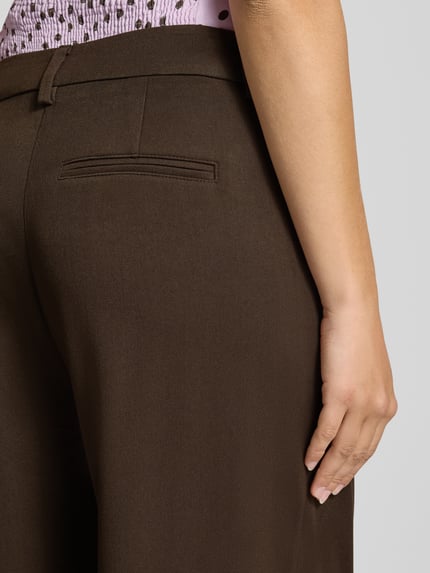Mädchen trägt braune spodnie z szerokimi nogawkami Wide Leg Hose mit Viskose-Anteil Modell 'PALINO' von ONLY, Damen Weite Hose von ONLY, Nahaufnahme Rückansicht