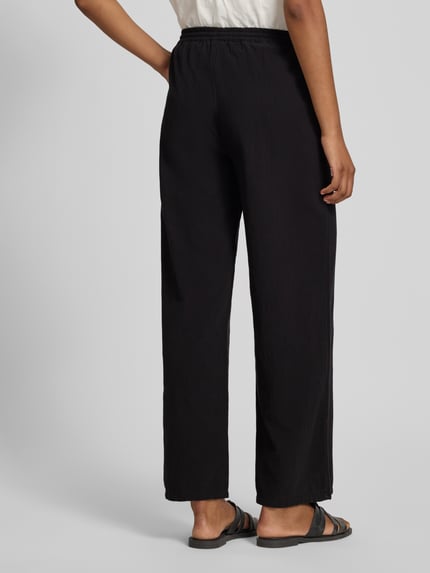 Frauenmodel trägt schwarze Stoffhose in verkürzter Passform Modell 'CISSIE' von Soyaconcept aus reiner Baumwolle mit elastischem Bund und Tunnelzug, Wide Leg, Ganzkörperansicht Rückansicht.