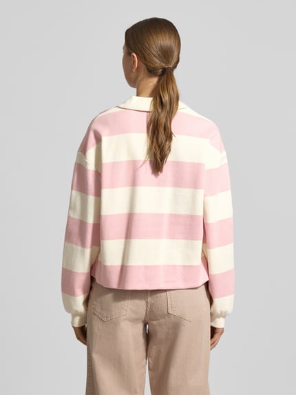 Modelka kobieca ma na sobie bluzę Sweatshirt mit Umlegekragen Modell 'Glocki' od OPUS, mieszanka bawełny i elastanu, prosty krój, wykładany kołnierz z dekoltem w serek, elastyczne wykończenia, widoczne różowe i białe szerokie paski, widok całej sylwetki od tyłu