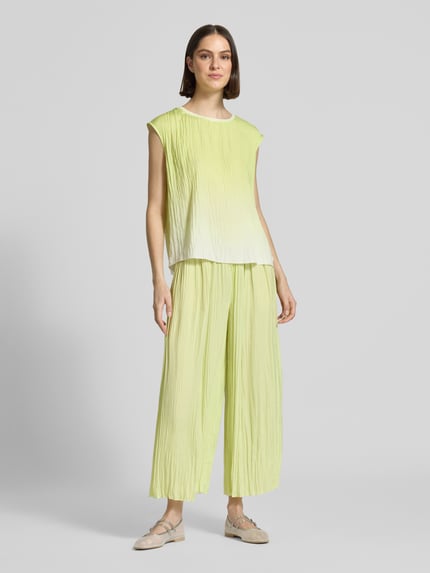 Frauenmodel trägt Pull-on-Hose mit Plisseefalten mit Tunnelzug von Marc Cain in Hellgelb, Relaxed-Fit, elastischer Bund, Label-Detail, Ganzkörperansicht von vorne.