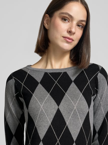 Frauenmodel trägt Strickkleid mit Seitenschlitzen von VERO MODA, mehrfarbig, geometrisches Muster, Rundhals, langarm, Nahaufnahme Oberkörper.