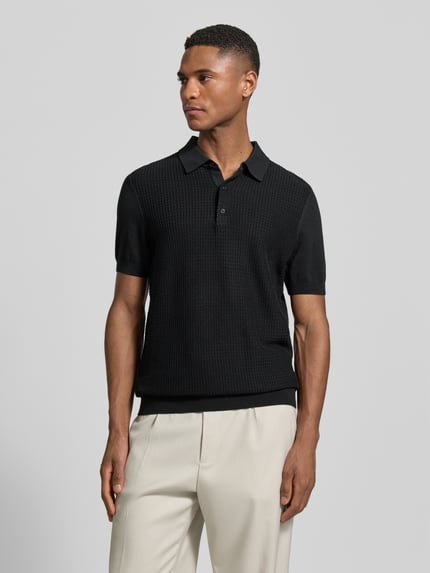 Männermodel trägt Regular Fit Poloshirt aus reiner Baumwolle von Strellson in Schwarz mit Strickoptik, kurzarm, Ganzkörperansicht von vorne.