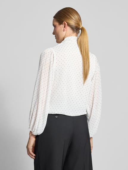 Frauenmodel trägt Schluppenbluse mit elastischen Ärmelabschlüssen Modell 'Dorellie' von Neo Noir, weiß mit schwarzen Punkten, Ganzkörperansicht Rückansicht. Damen Schluppenbluse, Regular Fit, Schluppe, Rückenlänge 51 cm, Ärmellänge 62 cm.