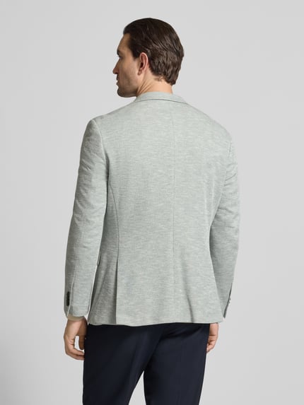 Männermodel trägt Slim Fit 2-Knopf-Sakko mit Pattentaschen von MCNEAL in lichtgrijs met structuur, rugaanzicht, materiaal-mix met katoen.