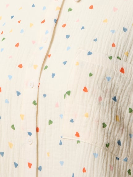 Frauenmodel trägt Relaxed Fit Pyjama-Oberteil im Allover-Look von Jake*s Casual aus reiner Baumwolle mit bunten Herzmustern, Nahaufnahme Oberkörper.