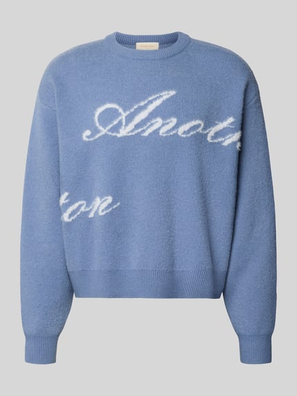 Produktfoto, Pullover mit geripptem Rundhalsausschnitt von ANOTHER COTTON LAB in Hellblau mit weißen Schriftzügen, gerader Schnitt, strukturierte Stricktextur, breite gerippte Abschlüsse, Rückenlänge 61 cm, Ärmellänge 63 cm.