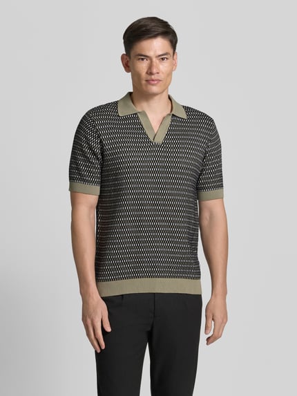 Männermodel trägt Relaxed Fit Strick-Poloshirt mit V-Ausschnitt von Lindbergh in Schwarz-Beige Allover-Look aus Reine Baumwolle, Ganzkörperansicht von vorne. Rückenlänge bei Größe M: 70 cm.