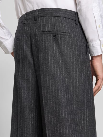 Männermodel trägt Relaxed Fit Stoffhose aus Baumwoll-Mix von Filippa K, Bundfalten, feine Nadelstreifen, Gesäßtasche, Nahaufnahme Rückansicht.