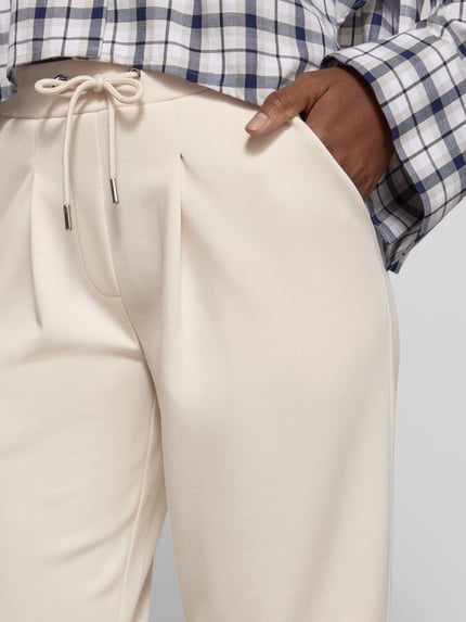 Frauenmodel trägt Sweatpants mit französischen Eingrifftaschen von monari in Creme, Material-Mix mit Viskose, Nahaufnahme Hüfte.