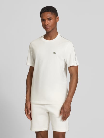 Männermodel trägt Regular Fit T-Shirt aus reiner Baumwolle von Lacoste in Unifarbe mit Label-Tape, Rundhals, Kurzarm, Ganzkörperansicht von vorne.