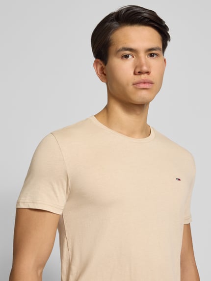 Mannelijk model draagt Regular Fit T-shirt uit katoenmix van Tommy Jeans met look: effen, gestikt logo, ronde hals, korte mouw, jersey. Nahaufnahme bovenlichaam.
