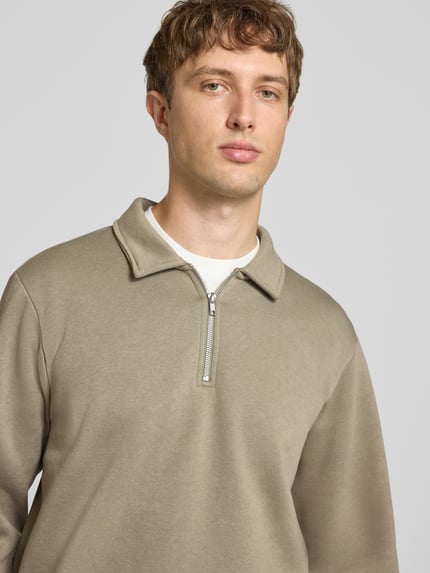 Męski model nosi Regular Fit Sweatshirt mit Baumwoll-Anteil Modell 'Bradley' von JACK & JONES, Mieszanka materiałów, kołnierz zapinany, zamek błyskawiczny, kolor beżowy, gładka tekstura, kontekst: bluza męska, długość tyłu w rozmiarze M: 69 cm, Nahaufnahme górnej części ciała.