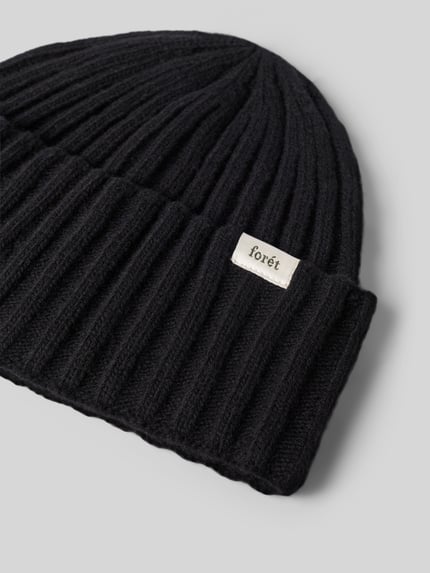 Produktfoto, Beanie aus Woll-Mix von Forét in dunkler Farbe, Ripp-Optik, breiter Umschlag, Label-Patch mit Logo-Schriftzug