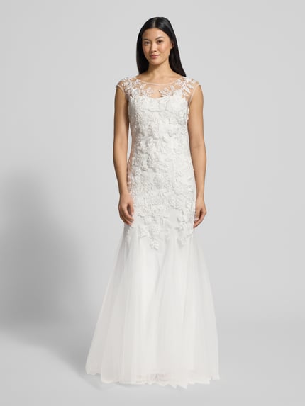 Frauenmodel trägt Brautkleid im Meerjungfrau-Stil von Mascara in Weiß mit floralen Stickereien, Herzausschnitt, breite Träger, Paillettenbesatz, Kurzarm, semitransparentes Obermaterial, blickdichtes Unterkleid, seitlicher Haken- und Nahtreißverschluss, Rückenlänge 150 cm, Brustweite 37 cm, Ganzkörperansicht von vorne.