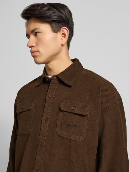 Männermodel trägt Freizeithemd mit Knopfleiste von Pegador aus reiner Baumwolle, Regular-Fit, Kentkragen, Brusttaschen, Label-Stitching, Nahaufnahme Oberkörper