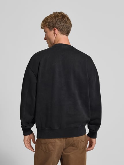 Männermodel trägt Relaxed Fit Sweatshirt aus Baumwoll-Mix von PEGADOR in Schwarz mit gerippten Bündchen und Logo-Stickerei, Ganzkörperansicht Rückansicht.