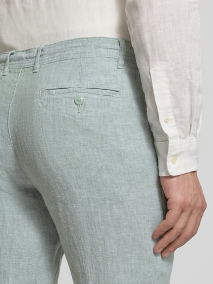 Männermodel trägt Leinenhose mit Schnürung und Gesäßtaschen von MCNEAL in hellem Grün, reine Leinenstruktur, Nahaufnahme Rückansicht.