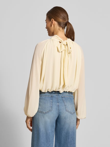 Frauenmodel trägt Regular Fit Bluse mit rückseitiger Schnürung Modell 'NUBE' von MANGO, cremefarben, Strukturmuster, Ganzkörperansicht Rückansicht.