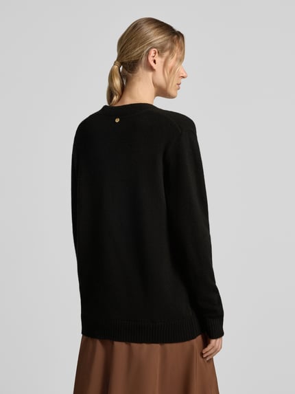 Frauenmodel trägt Relaxed Fit Cardigan aus reiner Wolle Modell 'Maglia Aperta' von Liu Jo White in Schwarz, Strick-Optik, Langarm, Ganzkörperansicht Rückansicht.