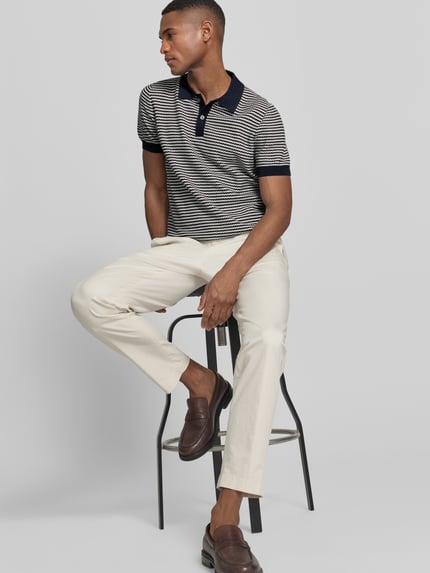 Męski model nosi Strickshirt mit Polokragen und Knopfleiste od Christian Berg Men, wzór w paski, krój regular fit, widok całej sylwetki z przodu.