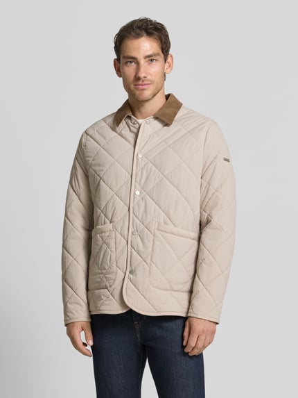 Männermodel trägt Steppjacke mit Eingrifftaschen von CINQUE in Beige mit Rautensteppung, kontrastivem Kragen, Nahaufnahme Oberkörper. Elastischer Material-Mix, gerade Passform, durchgehende Druckknopfleiste, aufgesetzte Taschen.
