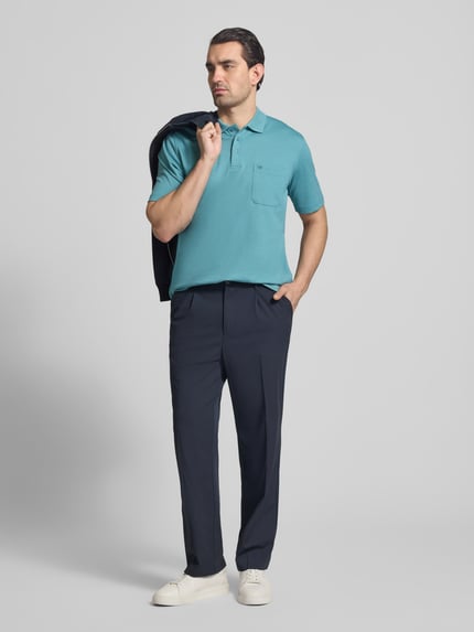 Męski model nosi Regular Fit Poloshirt mit Brusttasche von Christian Berg Men, mieszanka bawełny, kołnierzyk polo, listwa guzikowa, brustasza, długość tyłu w rozmiarze M: 68 cm, widok całej sylwetki z przodu