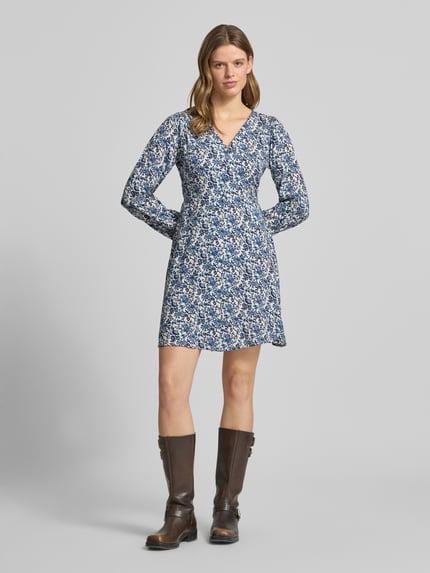 Frauenmodel trägt Tailliertes Freizeitkleid aus reiner Viskose Modell 'EVIDA' von Only, Optik: Allover-Muster, Mini-Länge, V-Ausschnitt, Knopfleiste, Langarm mit Ballonärmel, Ärmelabschluss mit Knopf und Öse, Material reine Viskose, Farbton überwiegend Blau mit weißen Akzenten, fließende Textur, Ganzkörperansicht von vorne.