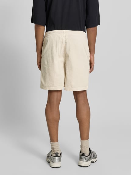 Männermodel trägt Shorts mit elastischem Bund Modell 'PADOW' von American Vintage, cremefarben, Baumwolle, lockerer Schnitt, Ganzkörperansicht Rückansicht.