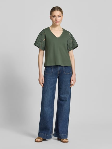 Frauenmodel trägt Regular Fit Blusenshirt aus reiner Baumwolle Modell 'VILLA' von Vero Moda, Optik: Unifarben, Spitzenbesatz, V-Ausschnitt, Kurzarm, Materialverarbeitung: Jersey, Ganzkörperansicht von vorne.