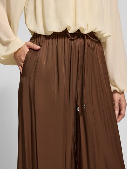 Frauenmodel trägt Weite Hose mit Tunnelzug von BOSS Orange in Braun mit elastischem Bund und geripptem Beinabschluss, Nahaufnahme Oberkörper.