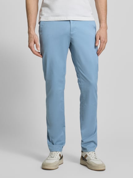 Męski model nosi Straight Fit Chino mit Eingrifftaschen von MCNEAL, jasnoniebieska mieszanka bawełny, wpuszczane kieszenie, zapięcie na guzik i zamek, szerokość w pasie 46 cm, długość wewnętrzna nogawki 81 cm, całkowity widok z przodu.
