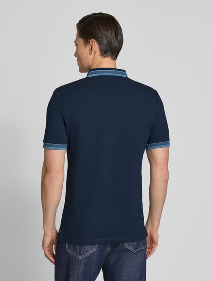 Męski model nosi Regular Fit Poloshirt aus Baumwoll-Mix von s.Oliver RED LABEL, kolor granatowy, tekstura piké, krój regular fit, gładki wzór, nadruk z logo, kołnierzyk polo, krótkie rękawy z ściągaczem, dół z rozcięciami po bokach, widok całej sylwetki z tyłu.